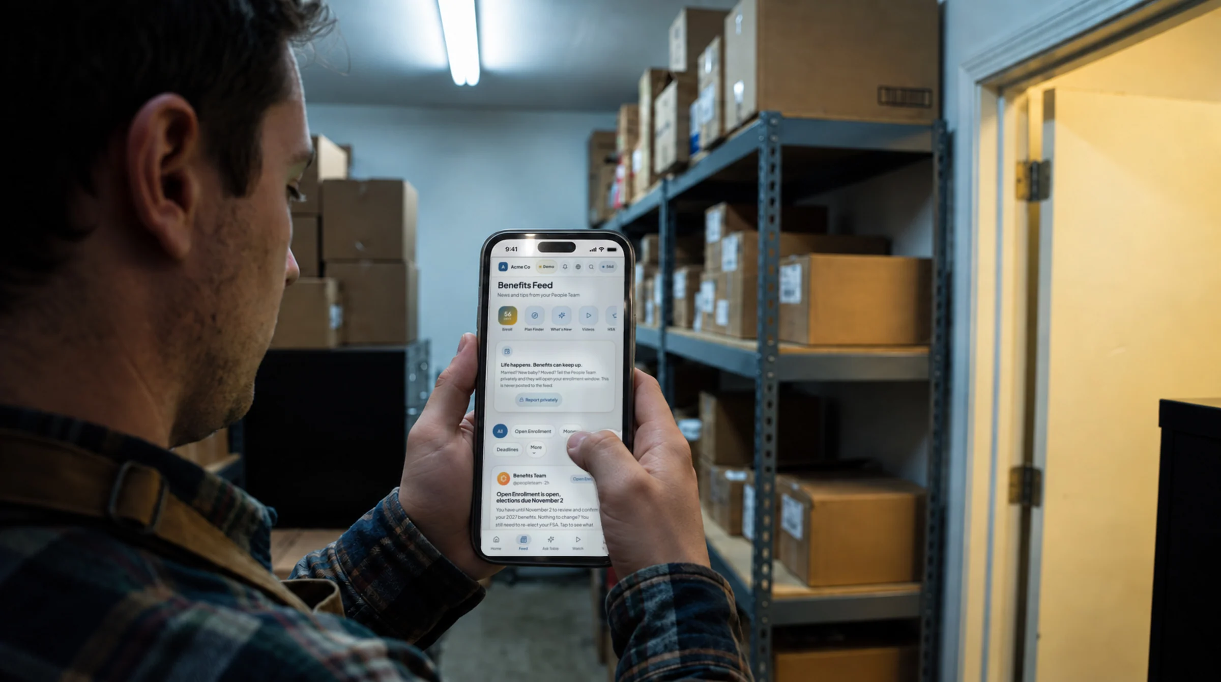 A retail associate on a break in a stockroom, reading the benefits feed on his phone
