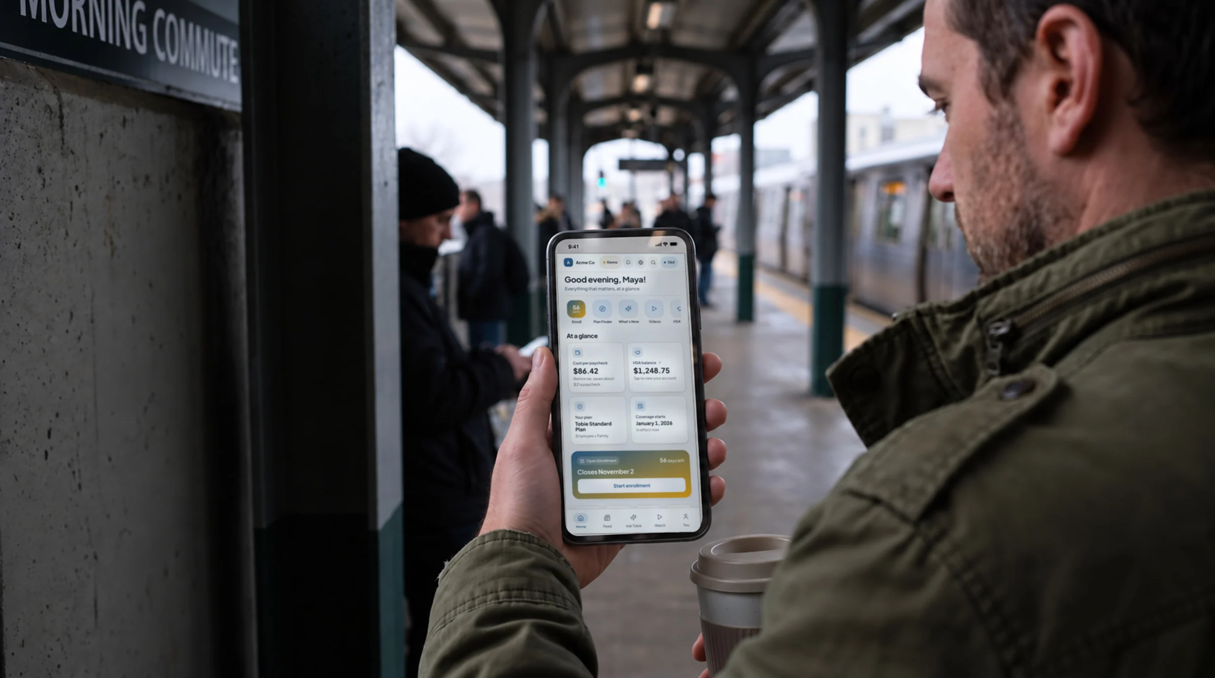 A commuter on a train platform in the morning, reading the benefits hub on his phone